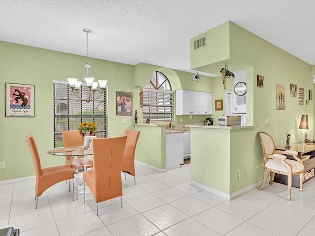 tiled dining area featuring a healthy amount of sunlight, a chandelier, and a textured ceiling