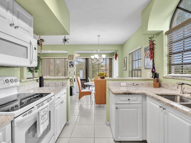 kitchen featuring pendant lighting, white appliances, white cabinets, an inviting chandelier, and sink