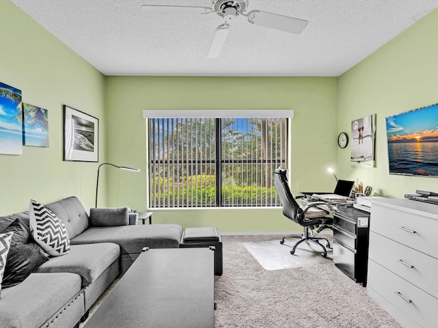 home office featuring carpet, ceiling fan, and a textured ceiling