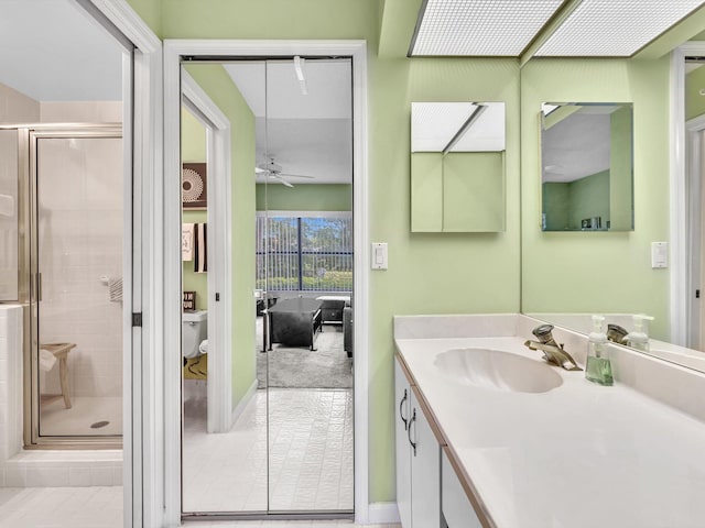 bathroom featuring ceiling fan, vanity, toilet, walk in shower, and tile patterned floors