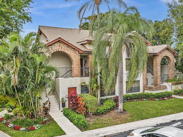 mediterranean / spanish-style home featuring a balcony and a front yard