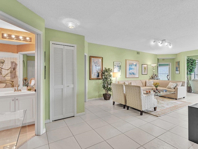 tiled living room with sink and a textured ceiling