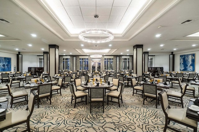 dining area with light colored carpet, a tray ceiling, crown molding, and an inviting chandelier