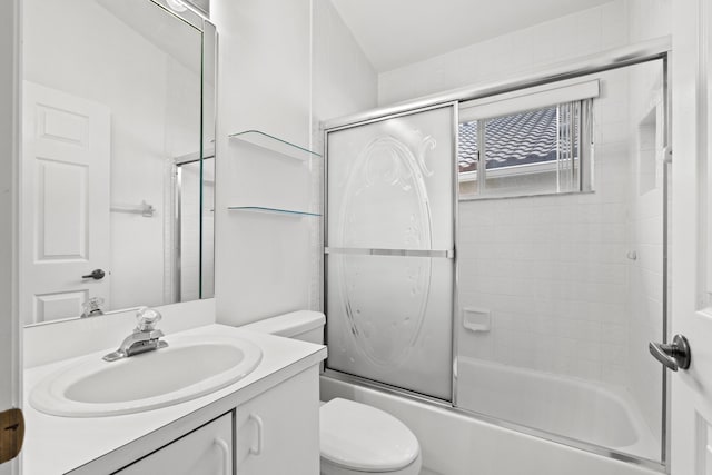 full bathroom featuring combined bath / shower with glass door, vanity, and toilet