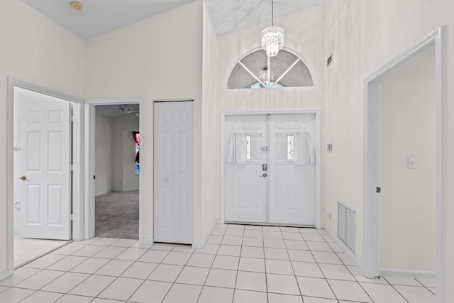 tiled entrance foyer with high vaulted ceiling and a chandelier