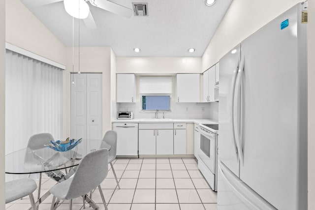 kitchen featuring lofted ceiling, tasteful backsplash, light tile patterned flooring, white appliances, and white cabinets