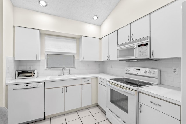 kitchen with white appliances, white cabinets, tasteful backsplash, sink, and light tile patterned floors