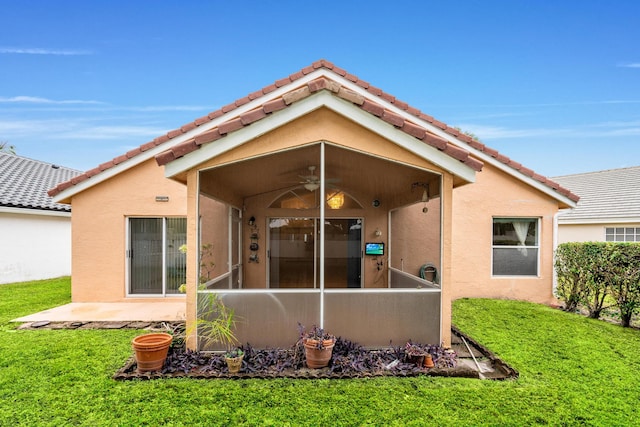 rear view of house with ceiling fan, a yard, and a patio