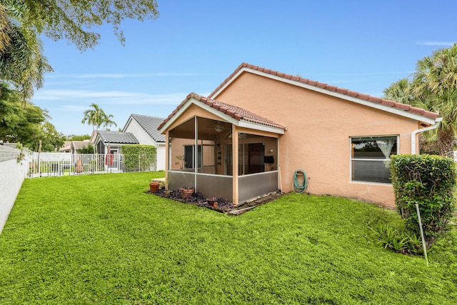 back of property featuring ceiling fan, a yard, and a sunroom