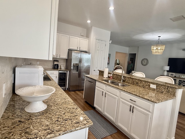 3289 Wymberly Dr, Jupiter, FL 33458 - kitchen with stainless steel appliances, beverage cooler, dark wood finished floors, white cabinetry, and a center island with sink