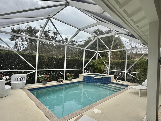 view of pool featuring glass enclosure, an in ground hot tub, and a patio