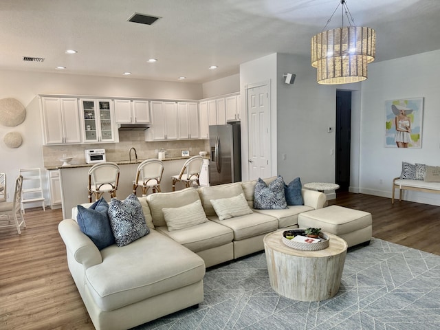 living room with a notable chandelier, light hardwood / wood-style floors, and sink