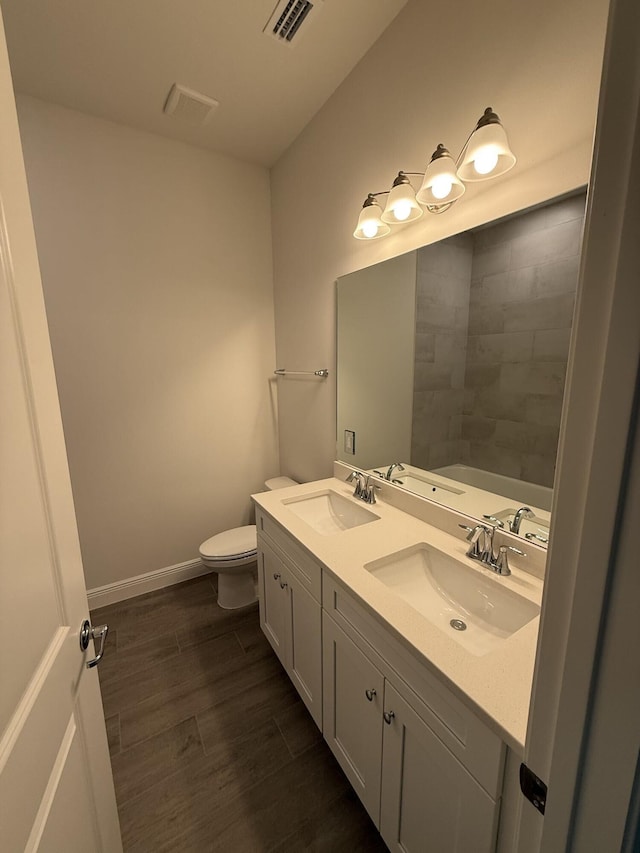 14042 82nd St N, The Acreage, FL 33470 - bathroom featuring toilet, double vanity, wood finished floors, baseboards, and a tub to relax in