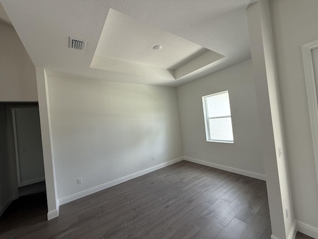 14042 82nd St N, The Acreage, FL 33470 - unfurnished bedroom with a tray ceiling, a textured ceiling, baseboards, and dark wood-type flooring
