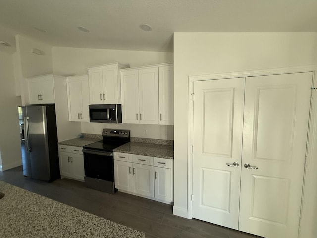 kitchen with white cabinetry, appliances with stainless steel finishes, stone countertops, and vaulted ceiling