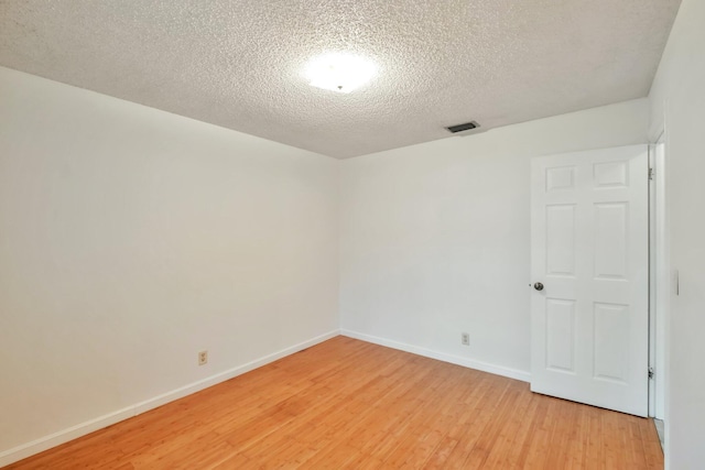 spare room with a textured ceiling and wood-type flooring