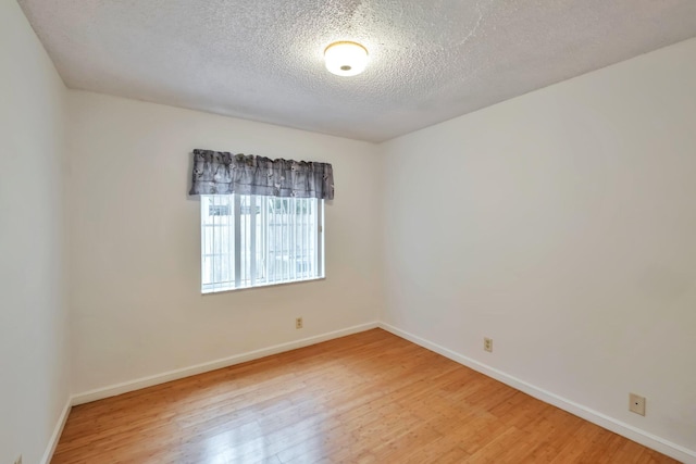 empty room featuring a textured ceiling and light hardwood / wood-style flooring