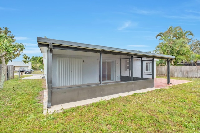 back of property with a sunroom and a lawn