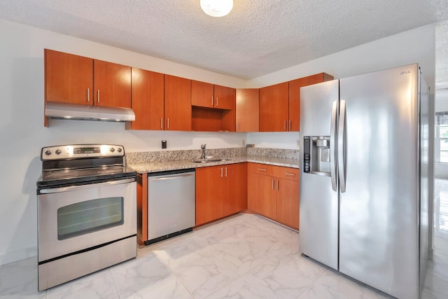 kitchen featuring light stone countertops, appliances with stainless steel finishes, sink, and a textured ceiling