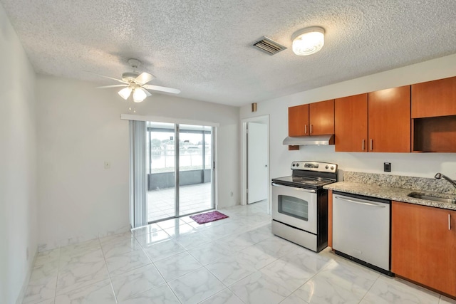 kitchen featuring ceiling fan, stainless steel appliances, a textured ceiling, light stone counters, and sink