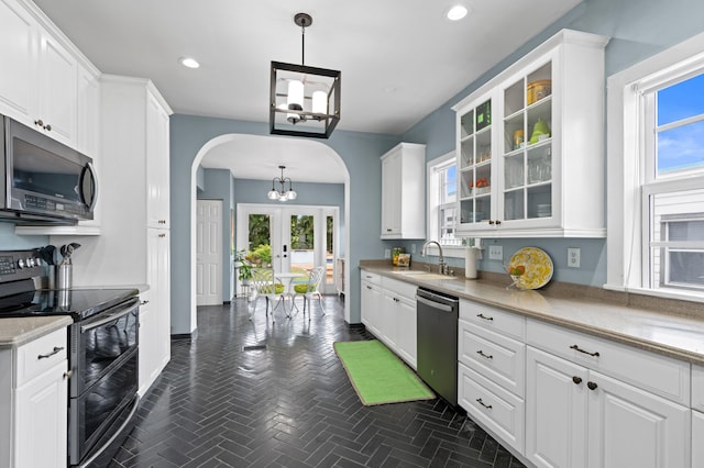 kitchen featuring appliances with stainless steel finishes, sink, white cabinets, and decorative light fixtures