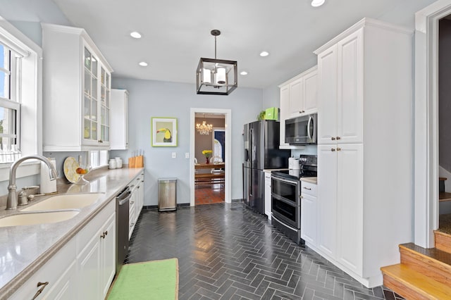 kitchen featuring decorative light fixtures, sink, white cabinetry, light stone countertops, and appliances with stainless steel finishes