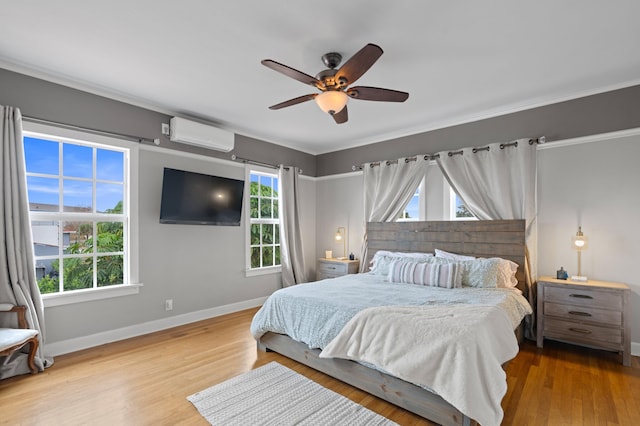 bedroom featuring light wood-type flooring, ceiling fan, and a wall mounted air conditioner