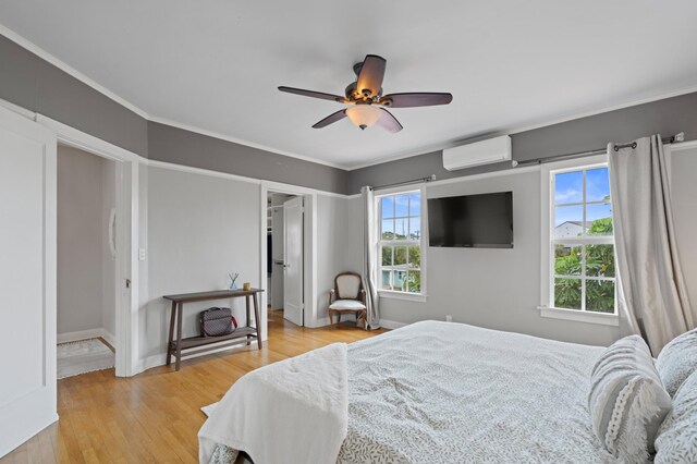 bedroom featuring ceiling fan, light hardwood / wood-style floors, an AC wall unit, and ornamental molding