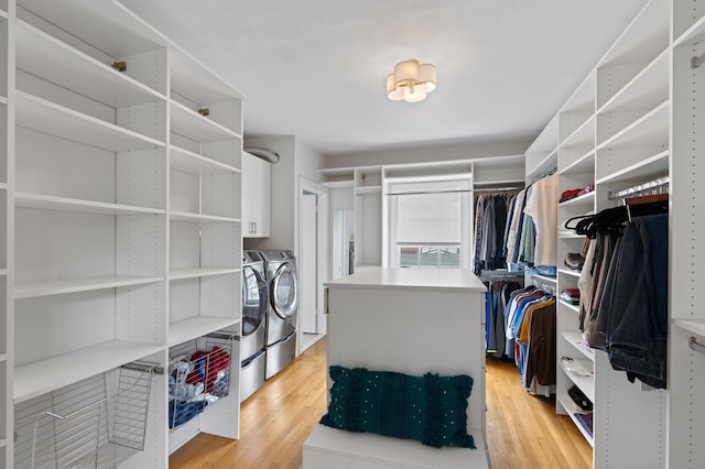 walk in closet with washer and dryer and light hardwood / wood-style floors