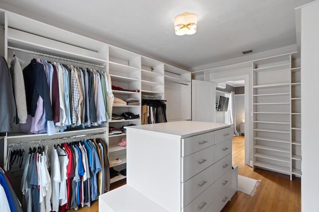 walk in closet with light hardwood / wood-style flooring