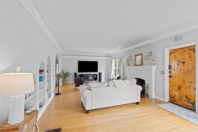 living room featuring built in features, ornamental molding, and light hardwood / wood-style flooring