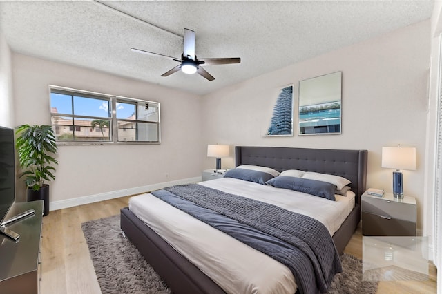 bedroom featuring light wood-type flooring, a textured ceiling, and ceiling fan