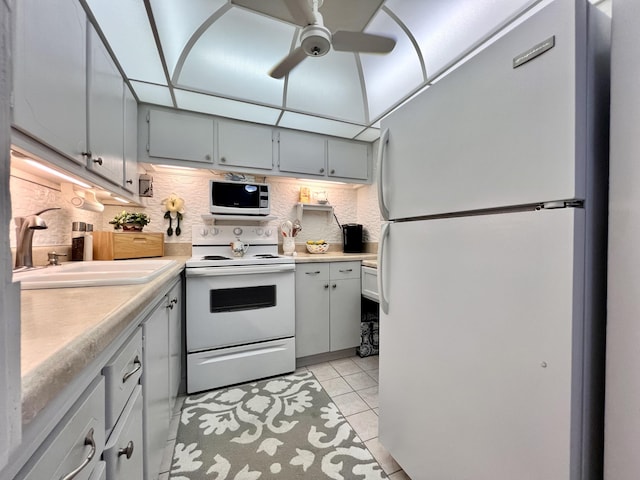 kitchen featuring ceiling fan, decorative backsplash, sink, white appliances, and light tile patterned floors