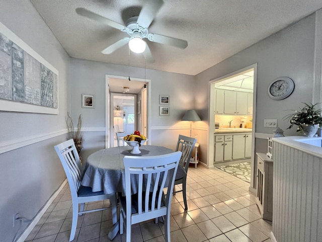 dining area featuring a textured ceiling, ceiling fan, light tile patterned floors, and sink