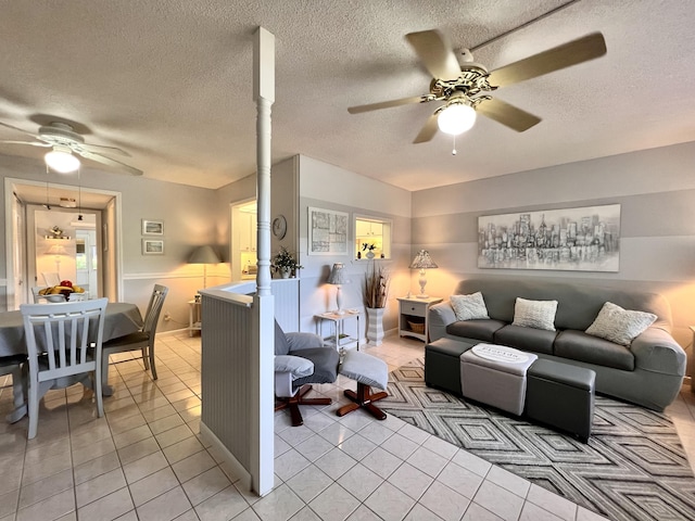 living room featuring ceiling fan, light tile patterned floors, and a textured ceiling