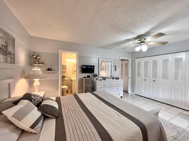 tiled bedroom featuring ceiling fan, a closet, connected bathroom, and a textured ceiling