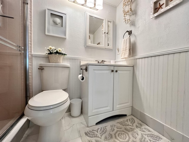 bathroom featuring toilet, a shower with shower door, and vanity