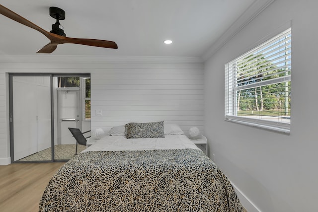 bedroom with wood walls, crown molding, a closet, ceiling fan, and hardwood / wood-style floors