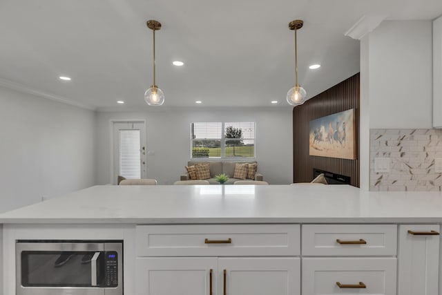 kitchen with white cabinetry, light stone counters, decorative light fixtures, and ornamental molding