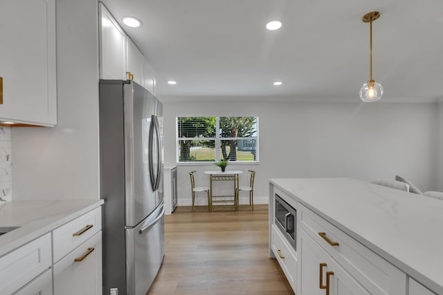 kitchen featuring pendant lighting, white cabinetry, stainless steel appliances, light stone countertops, and ornamental molding