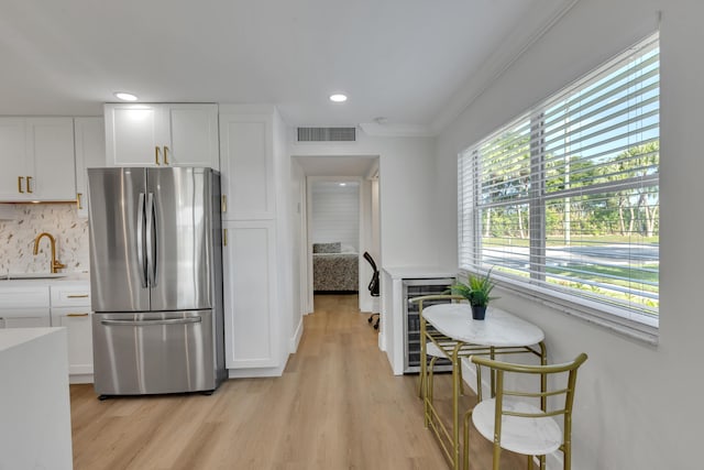 kitchen featuring stainless steel refrigerator, white cabinetry, sink, and backsplash