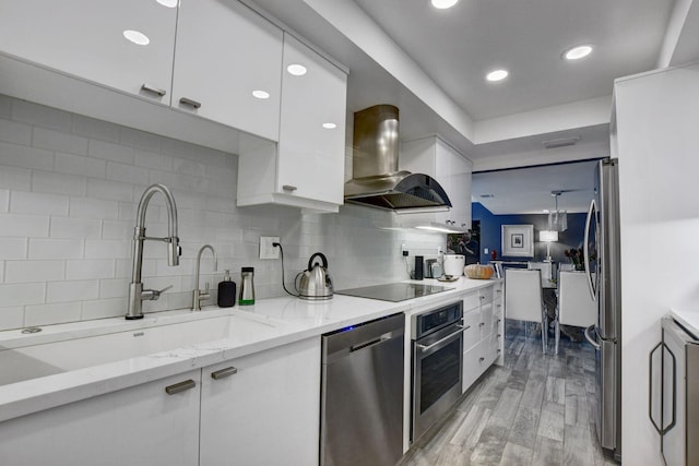 kitchen with extractor fan, sink, stainless steel appliances, white cabinets, and light stone counters