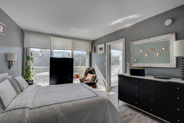 bedroom with access to outside, multiple windows, and light hardwood / wood-style flooring