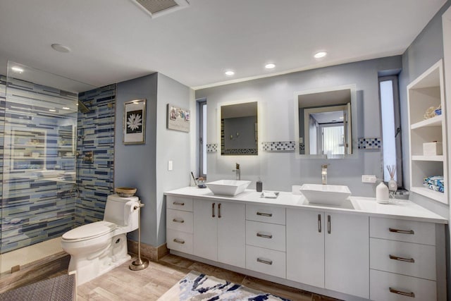 bathroom with toilet, a tile shower, and vanity