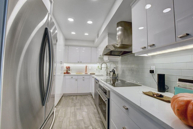 kitchen featuring appliances with stainless steel finishes, exhaust hood, white cabinetry, sink, and light wood-type flooring