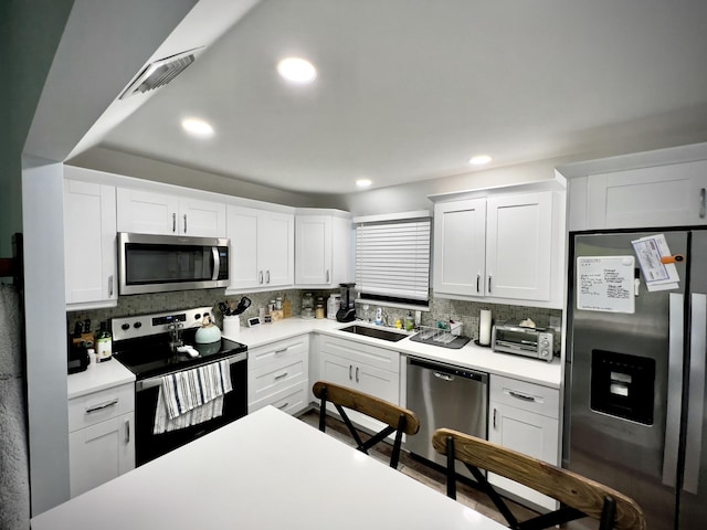 kitchen featuring stainless steel appliances, white cabinetry, sink, and decorative backsplash