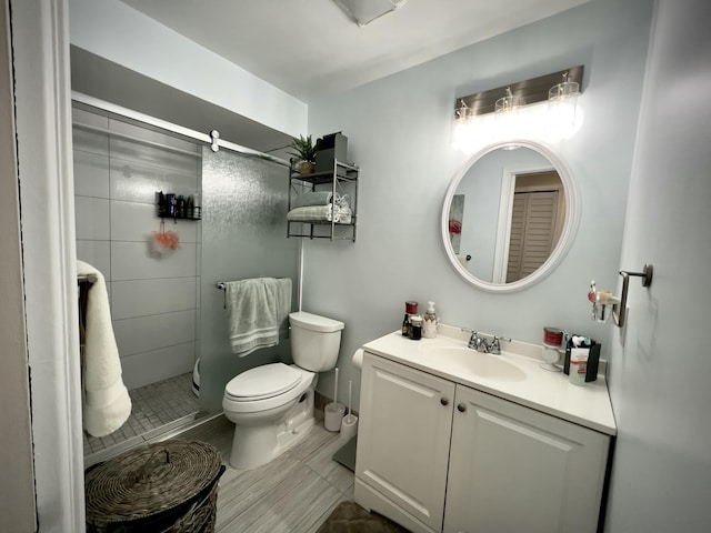 bathroom featuring vanity, a shower with door, and toilet