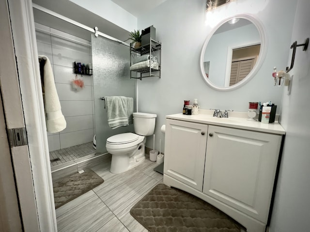 bathroom featuring tiled shower, vanity, and toilet