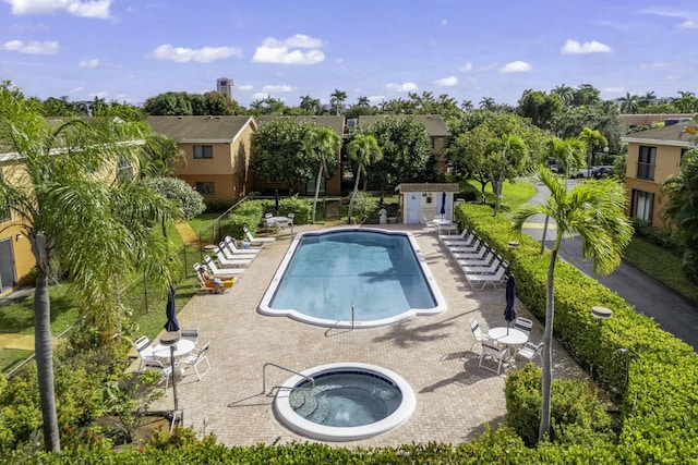 view of swimming pool featuring a shed, a community hot tub, and a patio