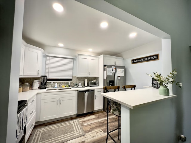 kitchen featuring white cabinetry, sink, a breakfast bar area, kitchen peninsula, and stainless steel appliances